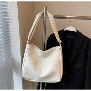 Close-up of off-white faux leather shoulder bag with lychee texture and adjustable strap