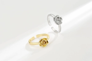 Detailed view of silver and gold rose rings with adjustable bands and 3D petals