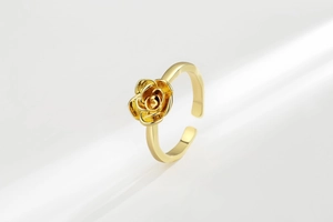 Macro view of gold rose petal layers and polished metal texture of the adjustable ring