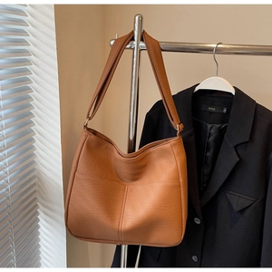 Detail of large brown lychee pattern leather tote bag with soft texture and shoulder strap