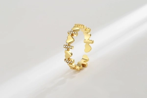 Detailed view of adjustable gold ring with heart and diamond-set cross motifs