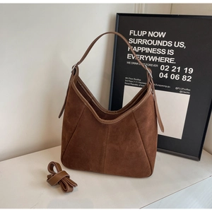 Detailed view of dark brown suede hobo bag with smooth minimalist cut and side fold design
