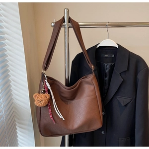 Detail of brown large tote bag with lychee texture and cute bear pendant accessory