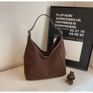 Detailed macro of dark brown suede bucket bag with vertical stitching and wide strap