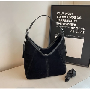 Detail of black suede Hobo bag featuring silver buckle strap and decorative stitching