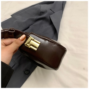 Detail of vintage coffee brown glossy leather shoulder bag with gold clasp and buckle