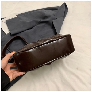 Detail view of the wide base and stitching on a dark brown glossy leather cloud bag