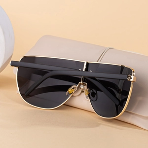Détail de lunettes de soleil à monture dorée posées sur un étui en cuir beige chic