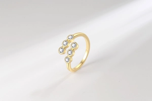 Detail eines verstellbaren Goldrings mit rundem, klarem Zirkonia in Zargenfassung