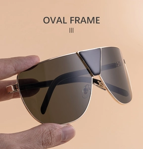Gros plan sur les lunettes aviateur dorées avec verres marron et détail triangulaire noir