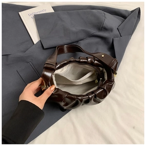 Interior detail of a brown cloud bag with light gray lining and a gold zipper pocket