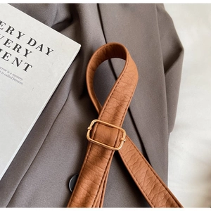 Detail of brown lychee grain leather strap with adjustable gold rectangular buckle