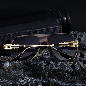 Detail einer Pilotenbrille mit goldenen Metallbügeln auf schwarzem Lavastein-Sockel