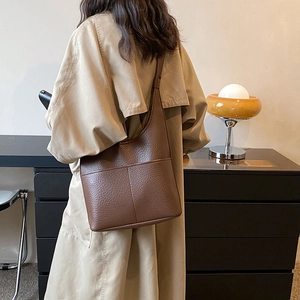 Large dark brown pebble leather hobo tote bag worn by model with beige trench coat