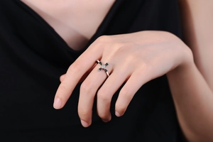 Detail of silver cross ring with black baguette stones and diamonds on finger