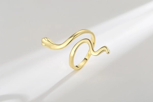 Macro shot of polished gold snake ring with S-curve design and sharp metallic reflections