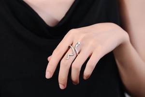 Close-up of minimalist silver snake-shaped ring on model's finger with 18K gold finish