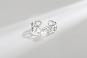 Detailed macro shot of a silver chain link ring with a white pearl and shadow light