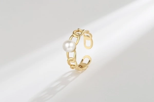 Detailed close-up of golden CD link ring featuring a white pearl and adjustable band