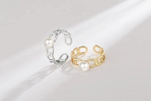 Detail view of gold and silver open chain rings featuring central white pearls