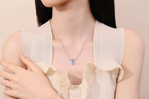 Detailed view of water drop blue gemstone necklace with silver bow on a female model