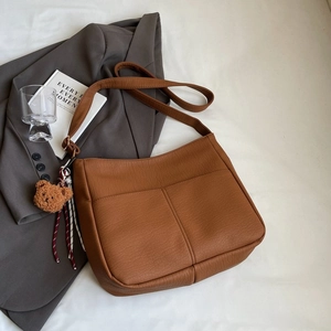 Macro shot of brown pebble grain tote bag texture with a cute plush bear charm detail