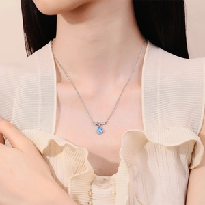Elegant silver necklace featuring a teardrop blue sapphire pendant on female model