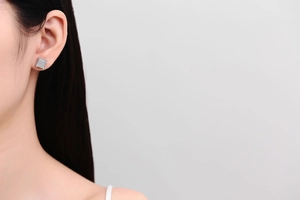 Gros plan d'une boucle d'oreille carrée en argent avec zircons sur un modèle