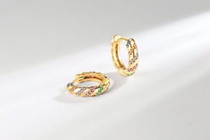 Close-up of golden hoop earrings with rainbow cubic zirconia and twisted rope texture