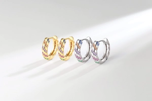 Macro view of gold and silver huggie hoop earrings with multi-color zircon stones