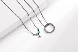 Dettaglio della collana vintage nera con foglia, gemma verde e pendente ad anello
