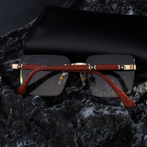 Detail of square rimless sunglasses featuring wood temples and gold metal accents