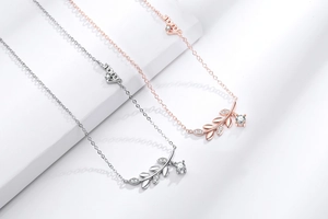 Détail du collier épi de blé en or rose avec pierres en zircon et breloques Love
