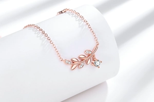 Détail du collier feuille de blé en or rose avec pendentif zircon et ombres élégantes