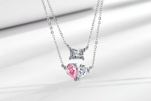 Detail of double-layer silver necklace with pink heart and rectangle zircon pendants