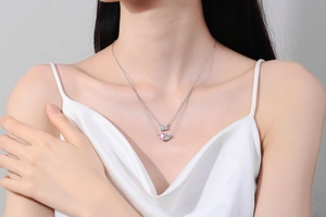 Close-up of double-layer necklace with pink heart and square zircon on model collarbone
