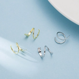 Minimalist double layer spiral hoop earrings in gold and silver finish on blue background