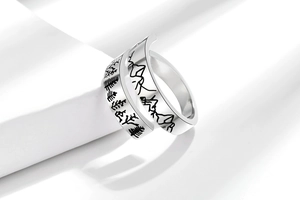 Detailed view of silver wrap ring featuring black etched mountain and pine forest pattern