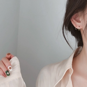 Detail showing two golden hoop earrings worn together for a minimalist layered style