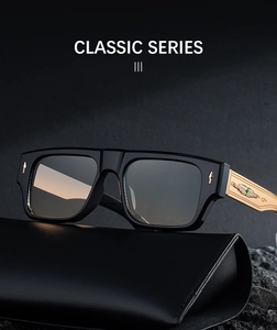 Detail of square black sunglasses with gold textured metal temples on leather case