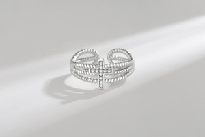 Macro detail of silver cross ring with white zircon stones and triple rope band texture