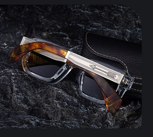 Détail macro du motif de flèche argentée sur branches ambre et monture transparente