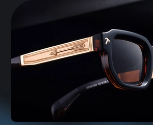 Détail de lunettes de soleil carrées montrant la branche dorée et le logo T gravé