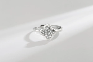 Macro shot of silver four-leaf clover ring with sparkling cubic zirconia on light background
