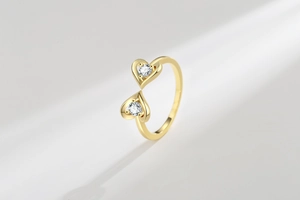Macro shot of double heart open ring in gold plating with sparkling white zircon stones