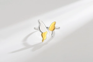 Detail of minimalist butterfly open ring with two-tone gold and silver metal finish
