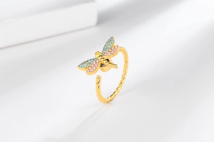 Detailed close-up of a golden spinning dragonfly ring with pink and blue cubic zirconia