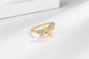 Detail of rotating dragonfly ring with blue and pink zircons on twisted gold band