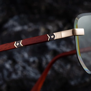 Detail einer randlosen Sonnenbrille mit Holzbügeln und goldenen Metallscharnieren