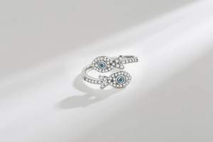 Macro detail of adjustable twin fish ring featuring zircon pavé and blue gemstone eyes